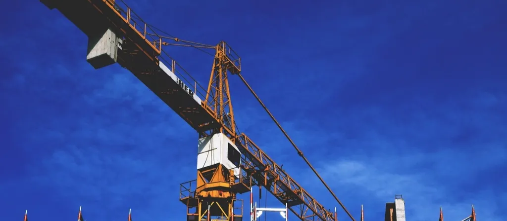 Tower crane over a building site against a blue sky