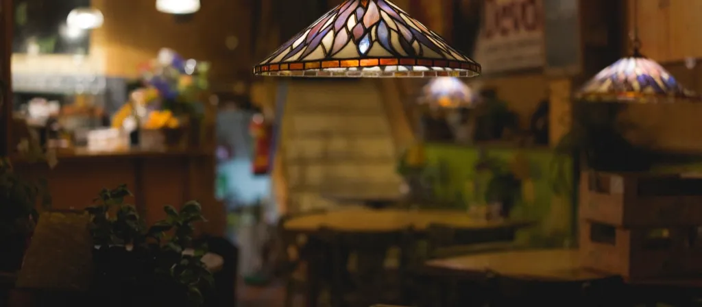 Warm restaurant interior with stained-glass lamps over wooden tables